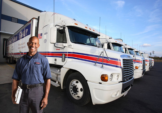 Truck driver standing in front of parked trucks